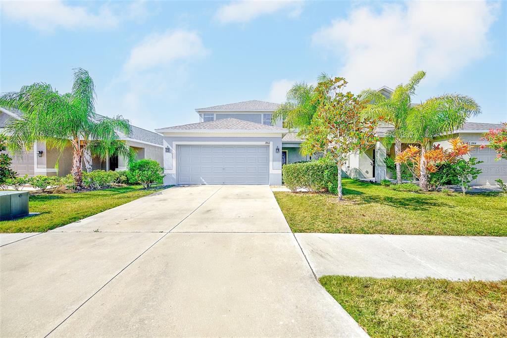 A two-story suburban house with a gray exterior, a two-car garage, and palm trees — 1902 HAWKS VIEW DRIVE, RUSKIN, FL