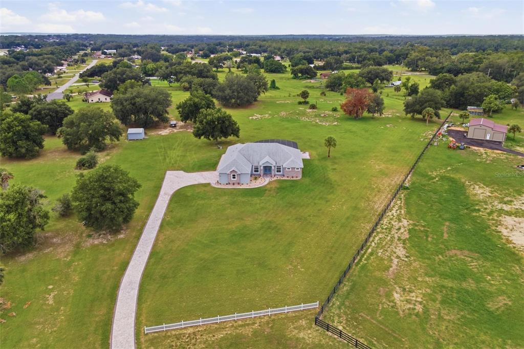 An aerial view shows a single-story house with a pool cage on a large rural lot — 5489 NANTAHALA LANE, LADY LAKE, FL