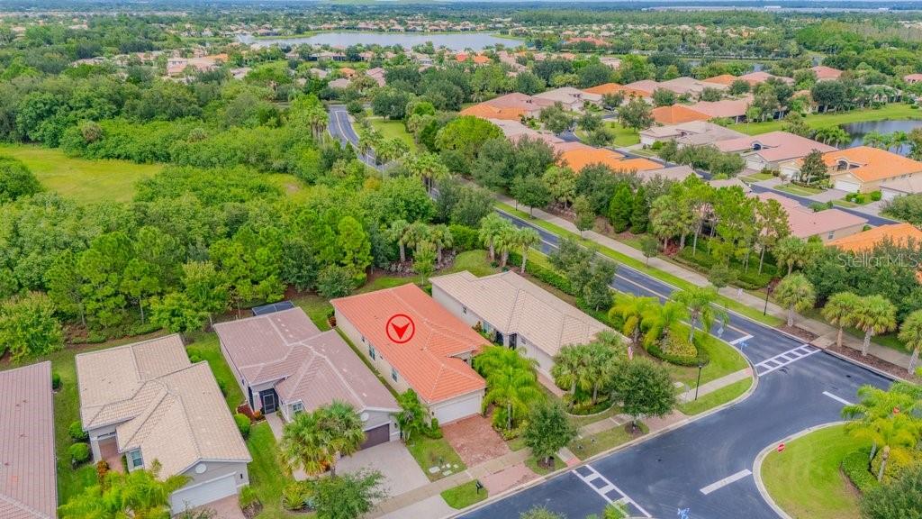 An aerial view shows a residential neighborhood with houses, green trees, and a nearby lake — 4952 SANDY GLEN WAY, WIMAUMA, FL
