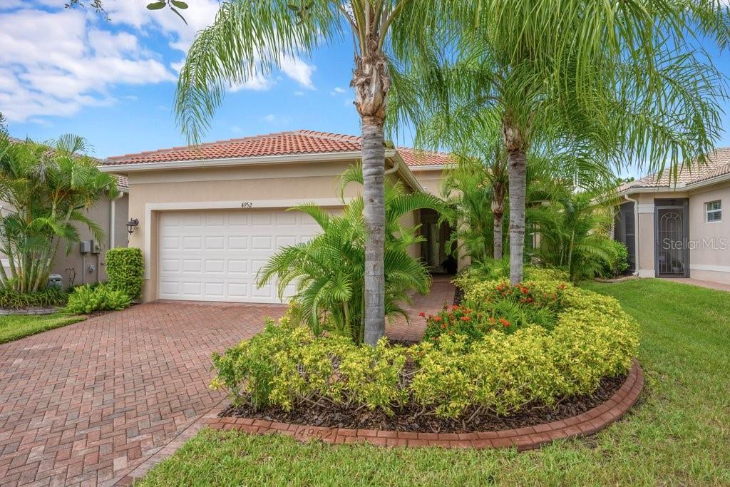 A single-story house with a brick driveway, a two-car garage, and palm trees in front — 4952 SANDY GLEN WAY, WIMAUMA, FL