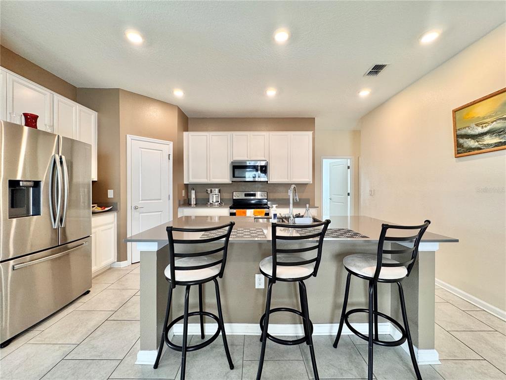 A kitchen features white cabinets, stainless steel appliances, a center island, and three bar stools — 913 WASHINGTON STREET, BARTOW, FL