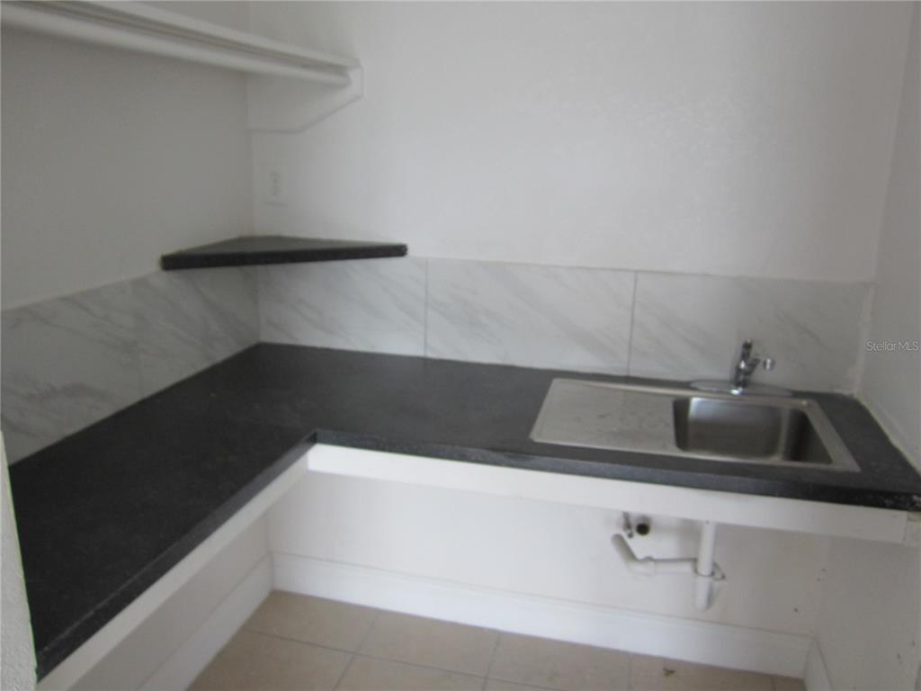 A laundry room or kitchenette features a dark countertop, stainless steel sink, and corner shelving — 4011 E COLUMBUS DRIVE, TAMPA, FL