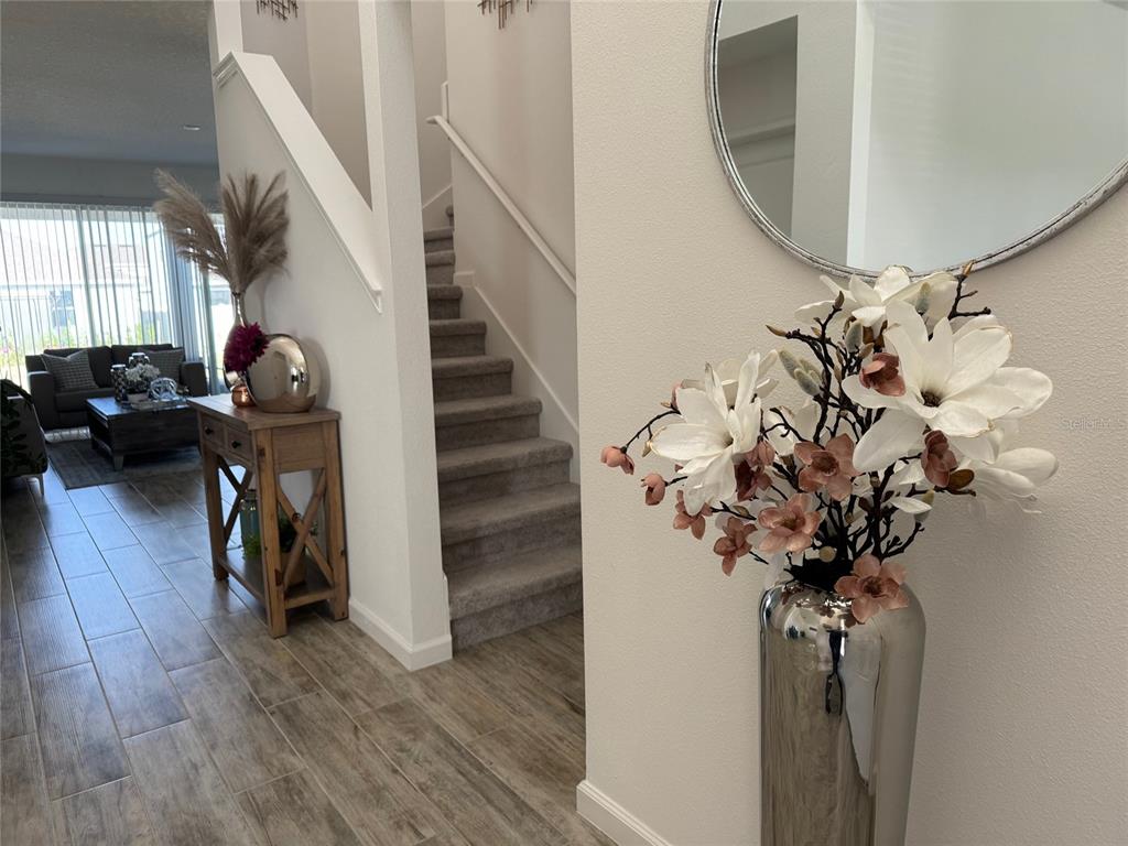 A foyer features a staircase, wood-look tile flooring, and a decorative floral arrangement — 380 CABELLO DRIVE, DAVENPORT, FL