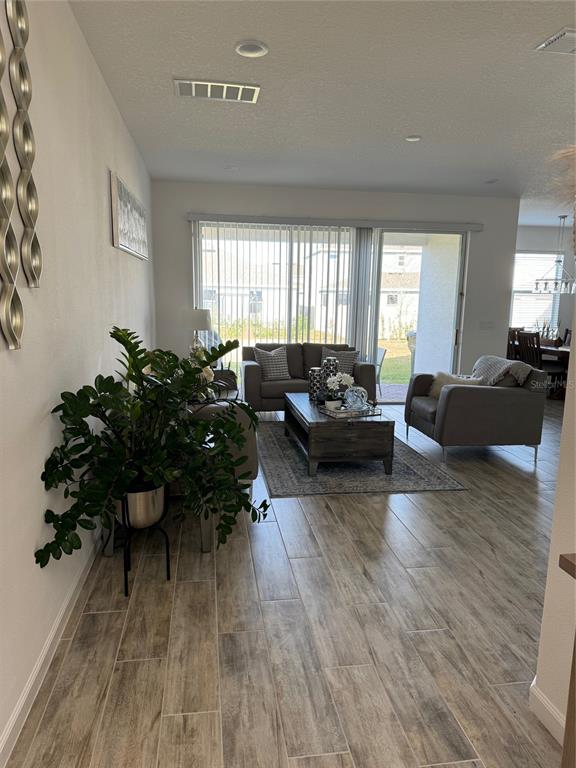 A living room features wood-look tile flooring, a seating area, and a sliding glass door — 380 CABELLO DRIVE, DAVENPORT, FL