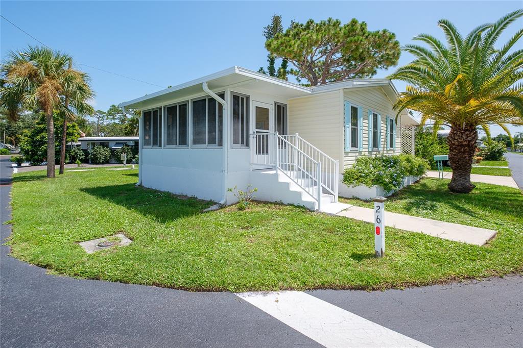 A single-story mobile home with a screened-in porch, white siding, and a palm tree — 1800 ENGLEWOOD ROAD UNIT 26, ENGLEWOOD, FL