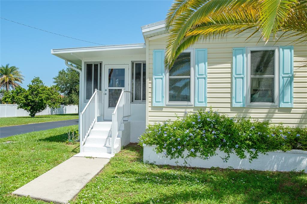 A light yellow mobile home with blue shutters, a white porch, and a palm tree — 1800 ENGLEWOOD ROAD UNIT 26, ENGLEWOOD, FL