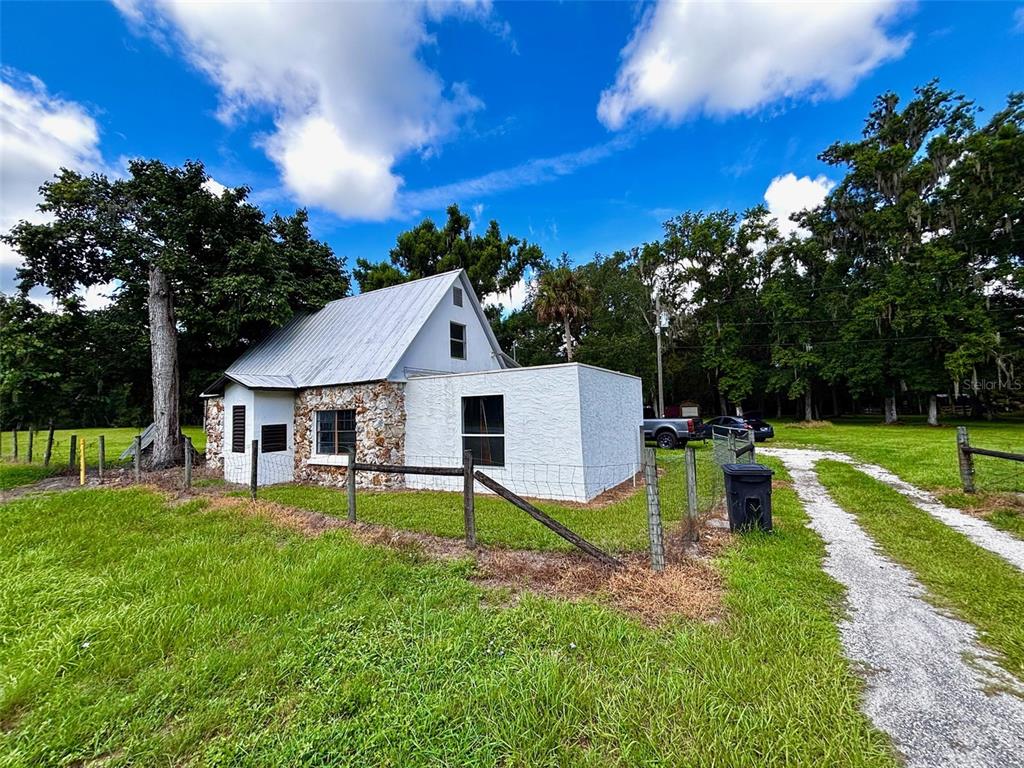 A small house with a metal roof, stone siding, and an attached white stucco addition — 9499 TREIMAN BOULEVARD, WEBSTER, FL