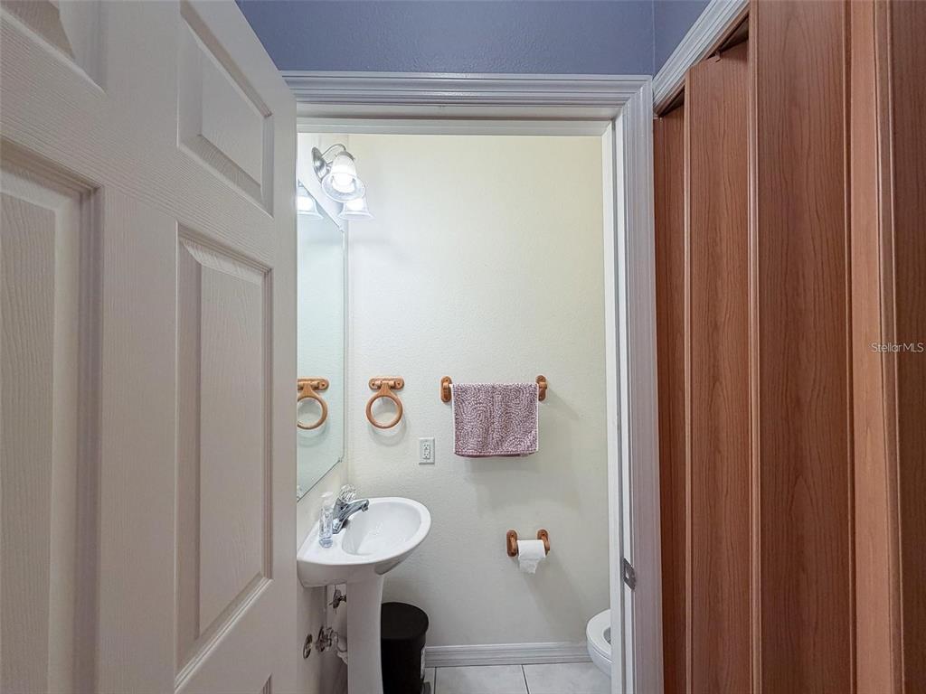 A small bathroom features a pedestal sink, a toilet, and a towel rack on the wall — 7669 PLANTATION CIRCLE, UNIVERSITY PARK, FL
