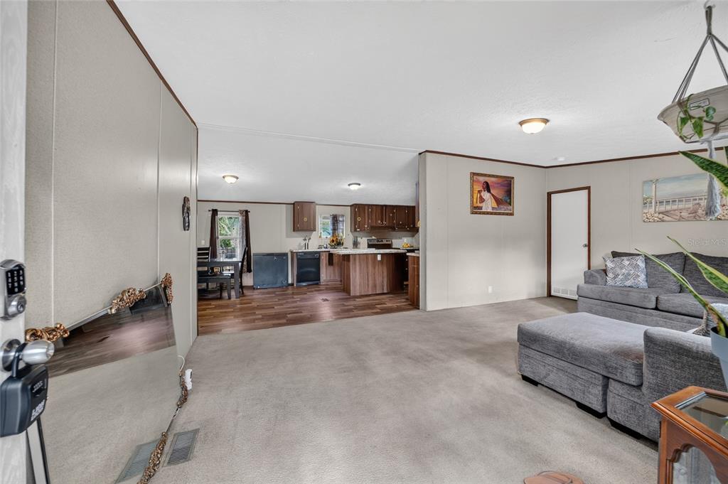 A living room with carpeted floors opens into a kitchen with wood cabinets and flooring — 4842 W NESTER COURT, HOMOSASSA, FL