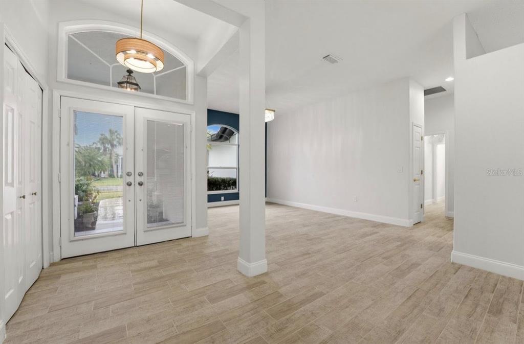 An entryway with light wood-look tile flooring, white walls, and double glass front doors — 507 CHEVAL DRIVE, VENICE, FL