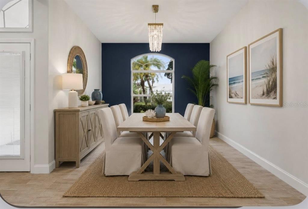 A dining room features a wooden table, slipcovered chairs, a navy accent wall, and a chandelier — 507 CHEVAL DRIVE, VENICE, FL