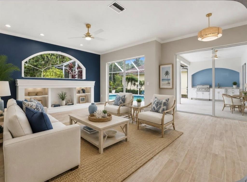 A living room with a blue accent wall, built-in shelving, and sliding doors to a patio — 507 CHEVAL DRIVE, VENICE, FL