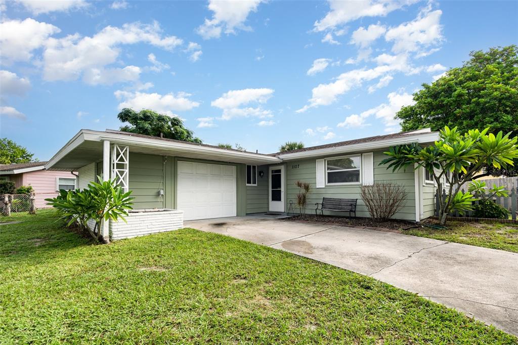 A single-story house with green siding, a white garage door, and a concrete driveway — 1107 CABLE LANE, PALM BAY, FL