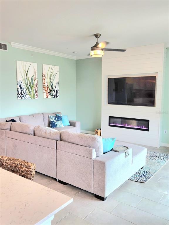 A living room features a light gray sectional sofa, a fireplace, and a ceiling fan — 18114 GAWTHROP DRIVE UNIT 103, BRADENTON, FL