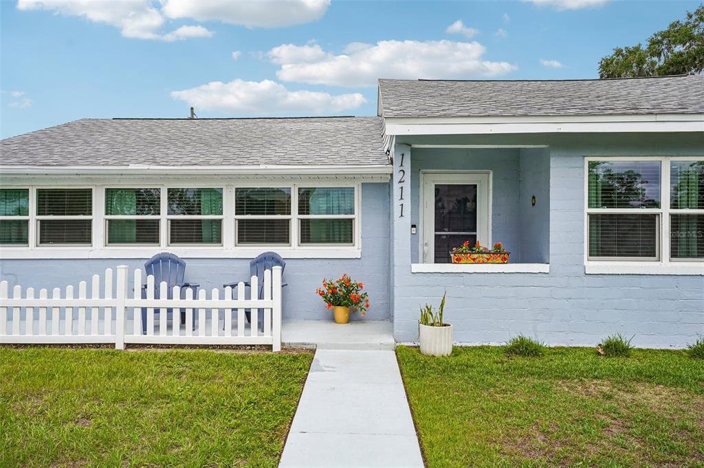 A light blue single-story house with a chimney and a manicured hedge in the yard — 1211 MORNINGSIDE DRIVE, MOUNT DORA, FL