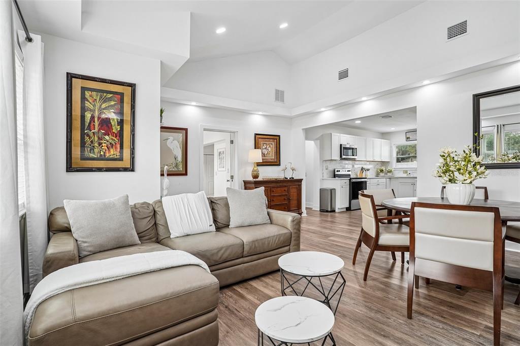 A living room with a sectional sofa and dining area flows into an open kitchen — 1211 MORNINGSIDE DRIVE, MOUNT DORA, FL