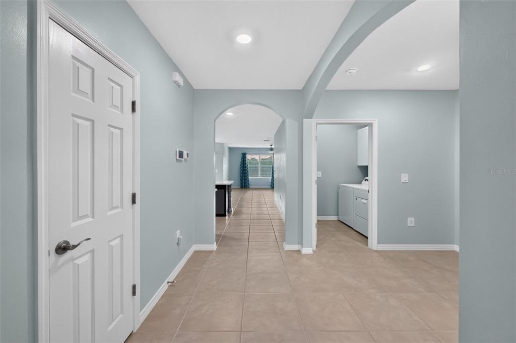 A hallway with light blue walls and tile flooring leads to an arched entryway — 4107 MANATEE LANE, PUNTA GORDA, FL