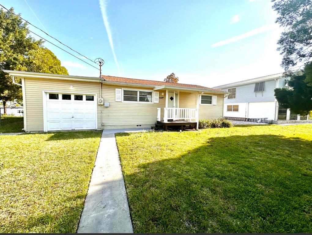 A single-story house with light yellow siding, a white garage door, and a front porch — 4016 EAGLE NEST DRIVE, HERNANDO BEACH, FL