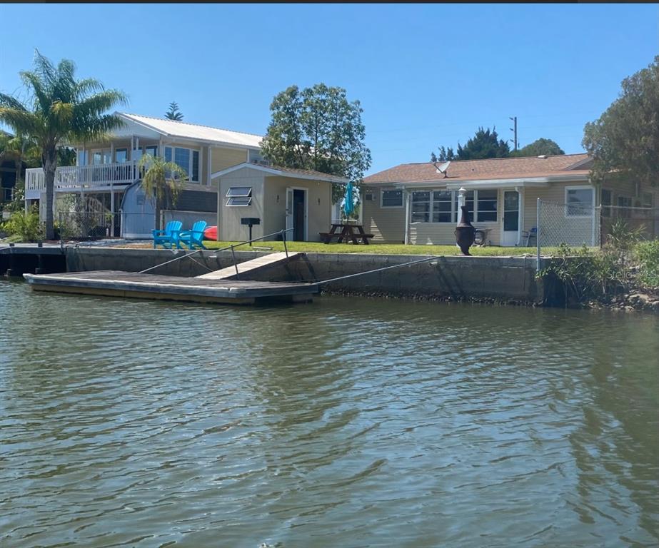 A waterfront property features a dock, a small shed, and two houses with grassy yards — 4016 EAGLE NEST DRIVE, HERNANDO BEACH, FL