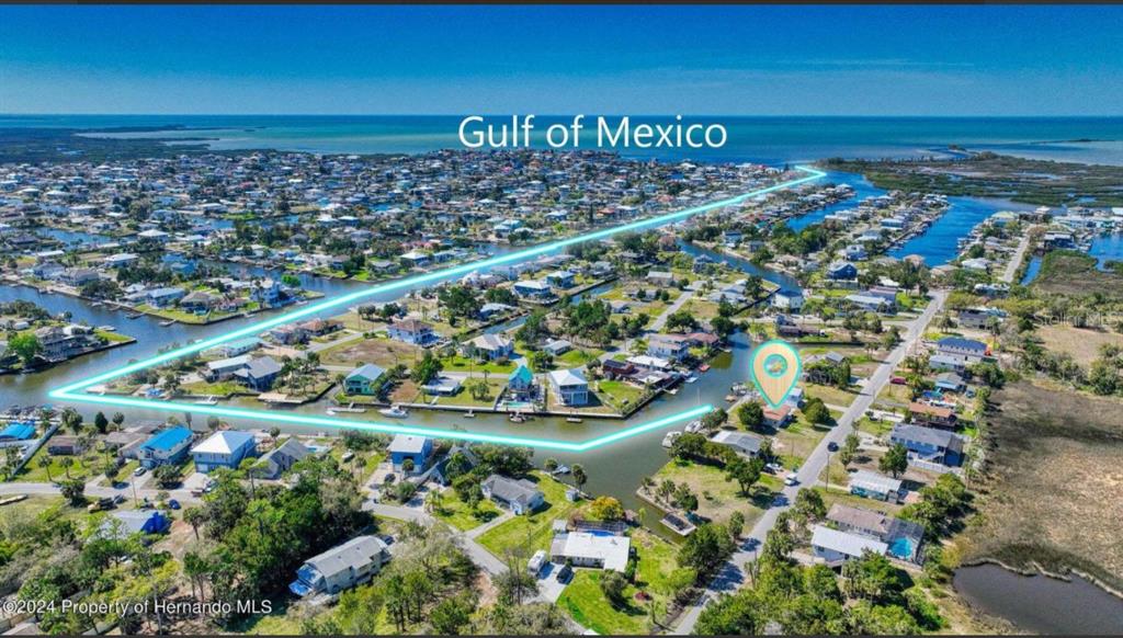 An aerial view shows a waterfront house with a canal and the Gulf of Mexico — 4016 EAGLE NEST DRIVE, HERNANDO BEACH, FL