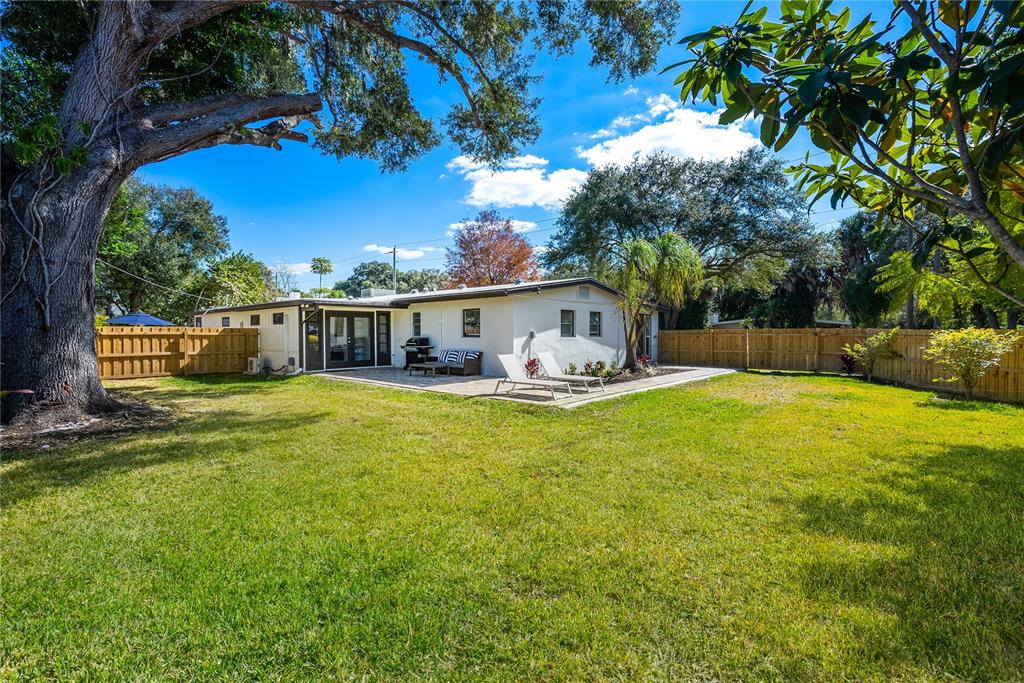 A backyard with a lawn, a paved patio, lounge chairs, and a wooden fence — 2311 WALDEMERE STREET UNIT A, SARASOTA, FL