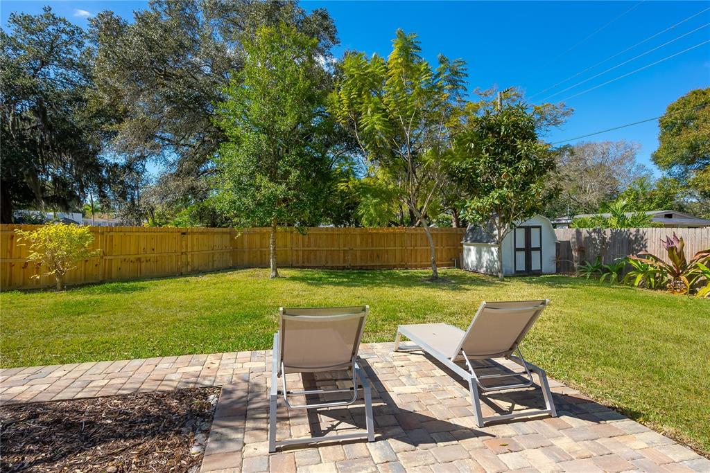 A backyard features a brick patio with two lounge chairs, a lawn, and a storage shed — 2311 WALDEMERE STREET UNIT A, SARASOTA, FL