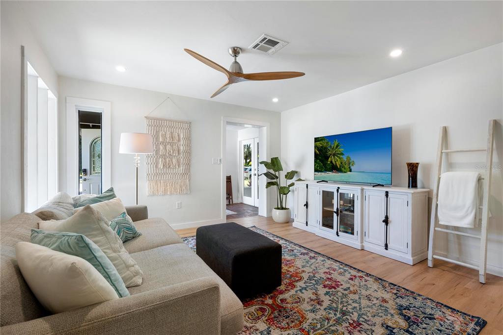 A living room features a sofa, patterned rug, television on a white console, and ceiling fan — 2311 WALDEMERE STREET UNIT A, SARASOTA, FL