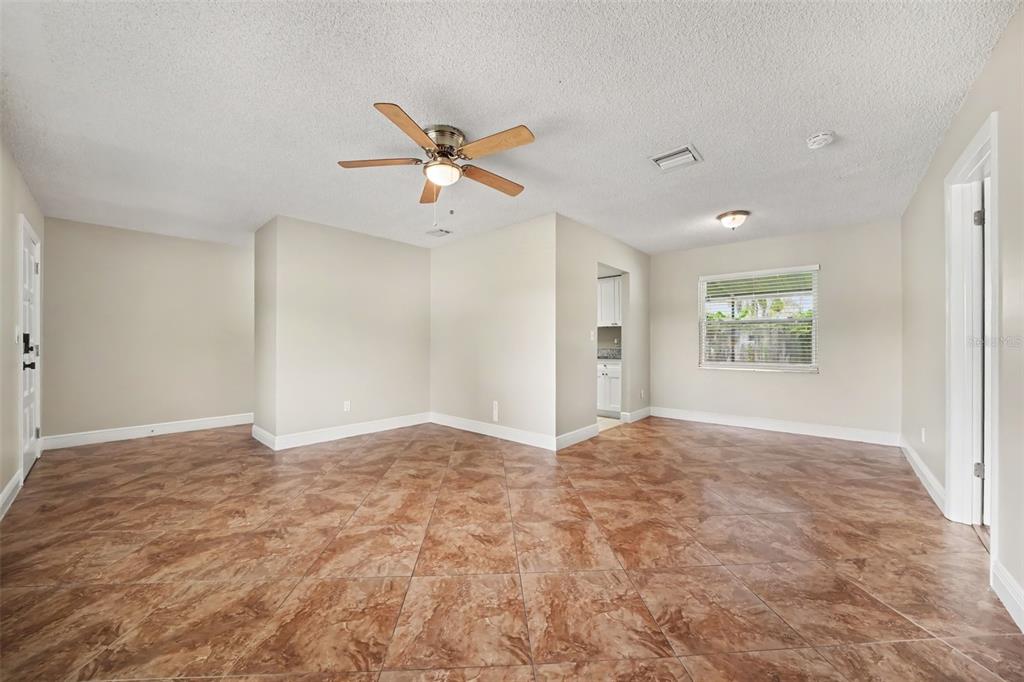 An empty room with tan tile flooring, a ceiling fan, and a window — 7925 SEGOVIA STREET, ORLANDO, FL