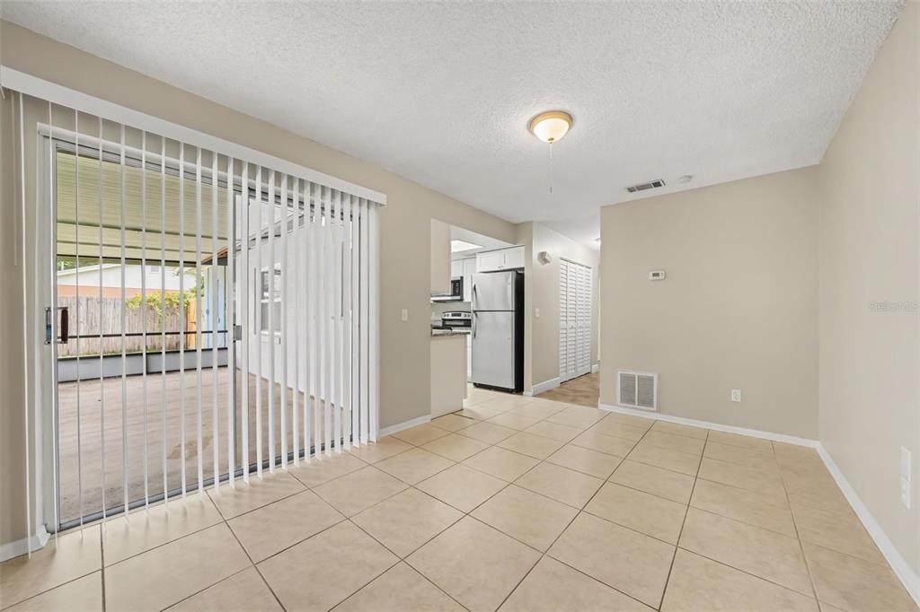 A tiled dining area features a sliding glass door leading to a covered patio — 7925 SEGOVIA STREET, ORLANDO, FL