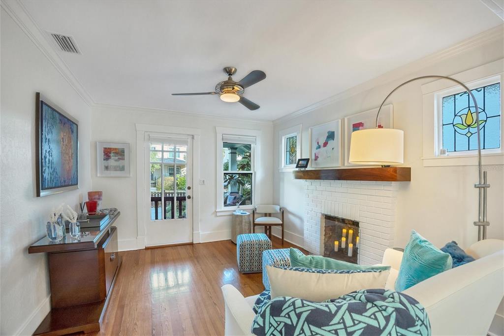 A living room features a white brick fireplace, hardwood floors, a ceiling fan, and furniture — 1716 OAK STREET, SARASOTA, FL
