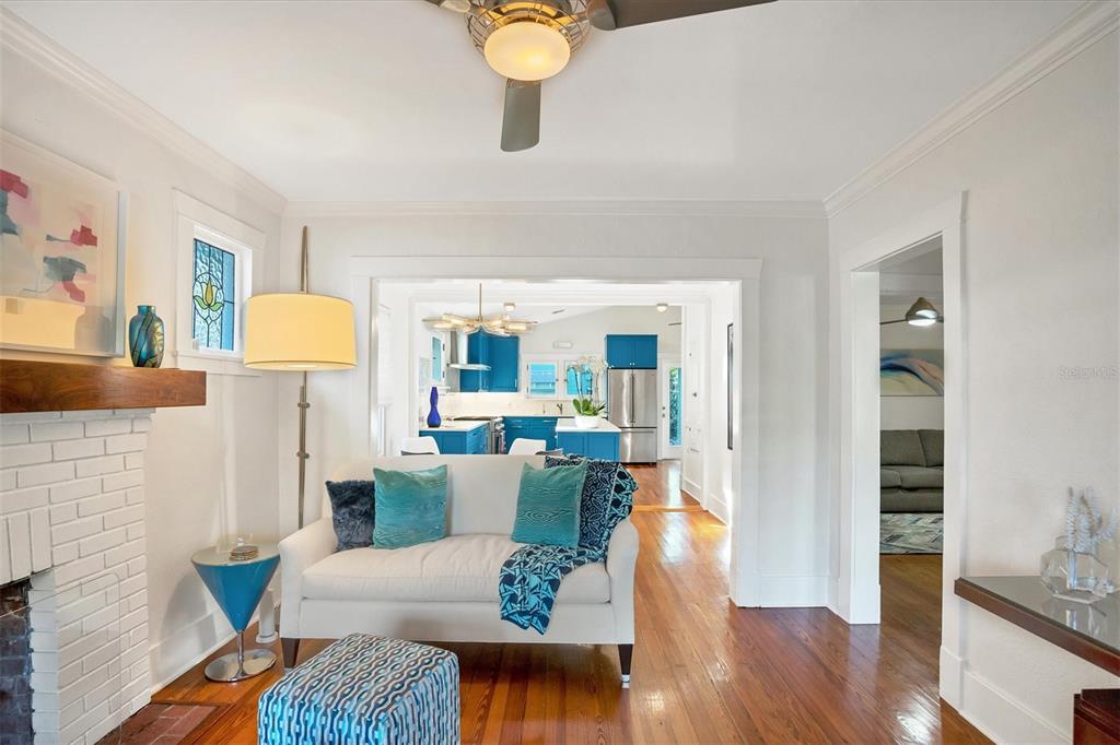 A living room with a white sofa and fireplace opens into a kitchen with blue cabinets — 1716 OAK STREET, SARASOTA, FL