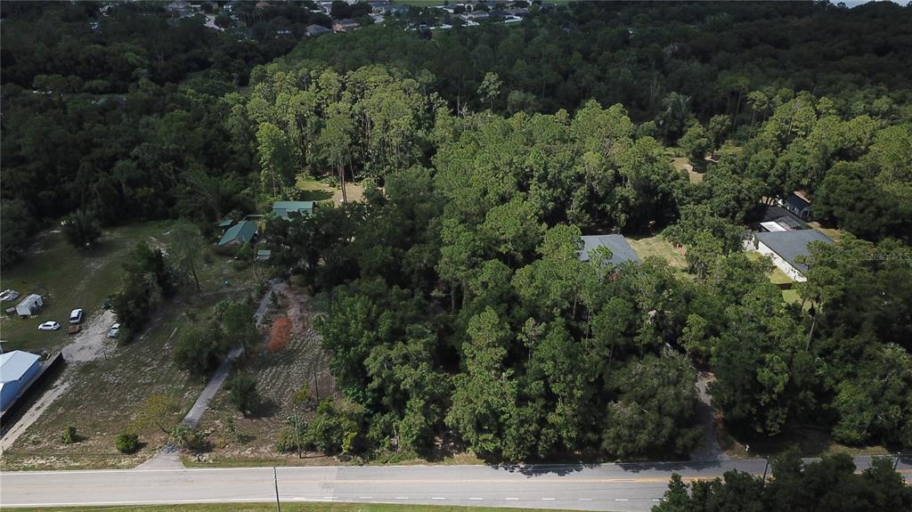 An aerial view shows a wooded lot with several houses and a road in front — E BATES AVENUE, EUSTIS, FL