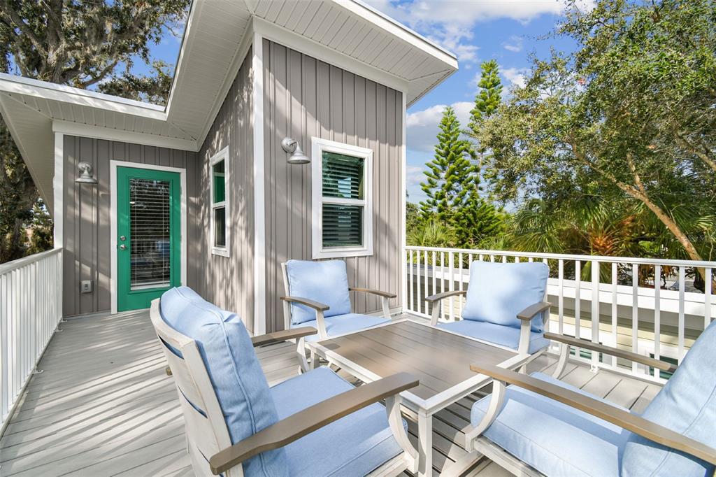 A gray wooden deck features four chairs with blue cushions around a central table — 1523 BAYSHORE BOULEVARD UNIT 3, DUNEDIN, FL
