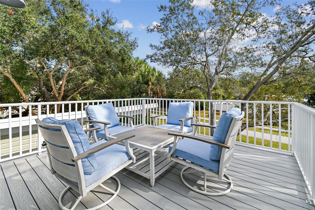 An outdoor deck features a square table and four blue-cushioned chairs surrounded by white railings — 1523 BAYSHORE BOULEVARD UNIT 3, DUNEDIN, FL