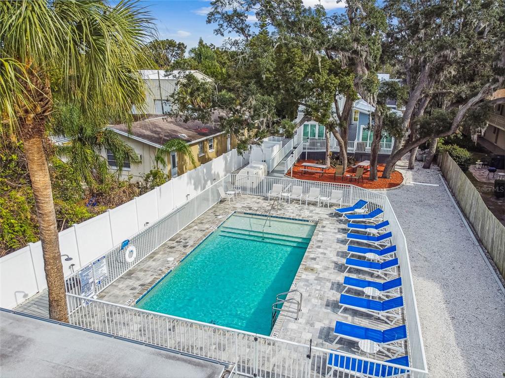An elevated view of a rectangular swimming pool surrounded by a white fence and lounge chairs — 1523 BAYSHORE BOULEVARD UNIT 3, DUNEDIN, FL