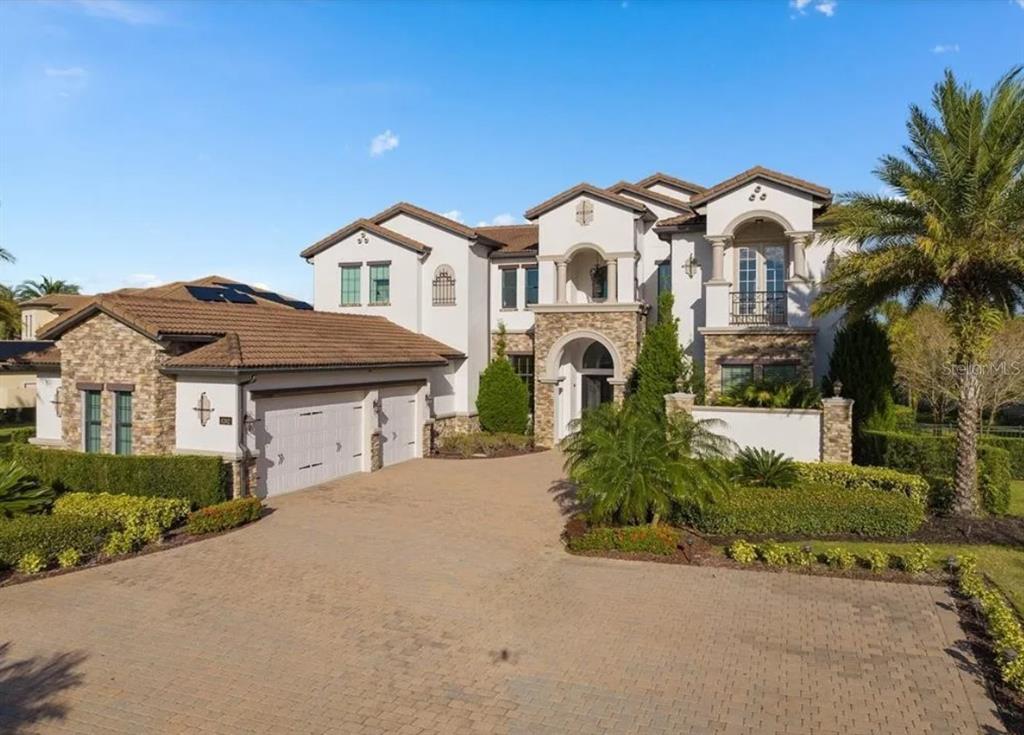 A large two-story Mediterranean-style house with a stone facade, tile roof, and paved driveway — 4302 ISABELLA CIR, WINDERMERE, FL