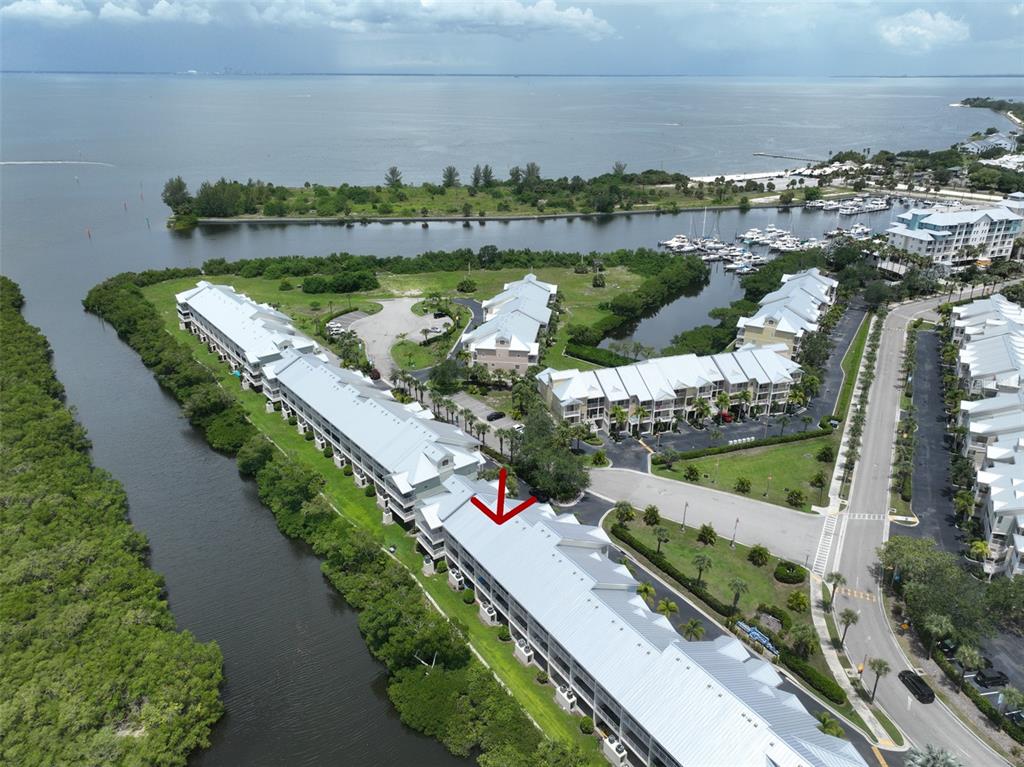 An aerial view shows a multi-story residential building complex situated along a coastal waterway — 3226 MANGROVE POINT DRIVE, RUSKIN, FL