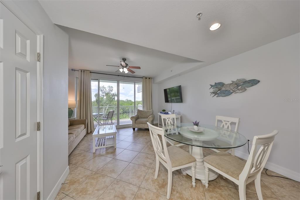 A living and dining area with tile floors, a glass-topped table, and a balcony view — 3226 MANGROVE POINT DRIVE, RUSKIN, FL