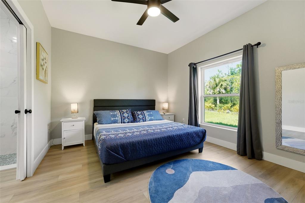 A bedroom features a bed with blue bedding, a ceiling fan, and a large window — 9409 AGATE STREET, PORT CHARLOTTE, FL