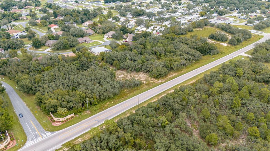 An aerial view shows a paved road running diagonally through a wooded residential area — COUNTY LINE ROAD, SPRING HILL, FL