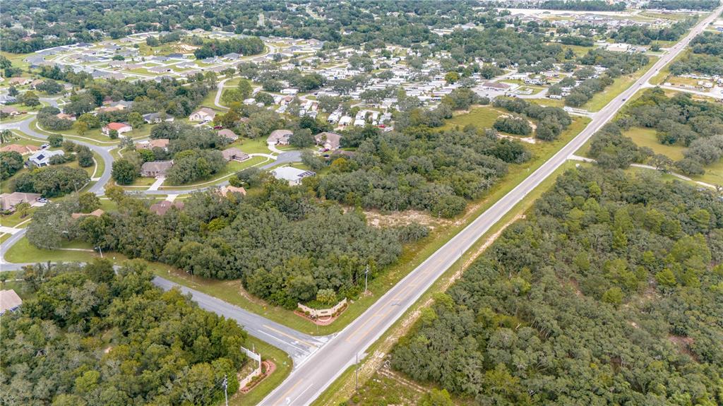 An aerial view shows a road bordering a wooded lot and a residential neighborhood — COUNTY LINE ROAD, SPRING HILL, FL