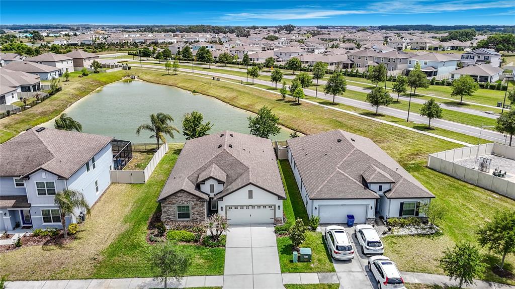 An aerial view shows suburban houses with driveways and a pond in a residential neighborhood — 30980 JAZZ LEAF PLACE, SAN ANTONIO, FL