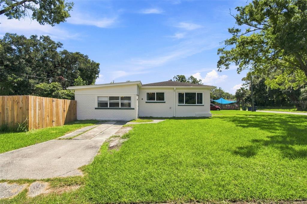 A single-story white brick house with a concrete driveway and a wooden fence — 2002 E HAMILTON AVENUE, TAMPA, FL
