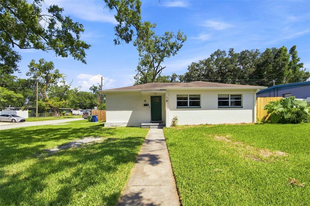 A single-story white brick house with a dark green front door and a concrete walkway — 2002 E HAMILTON AVENUE, TAMPA, FL
