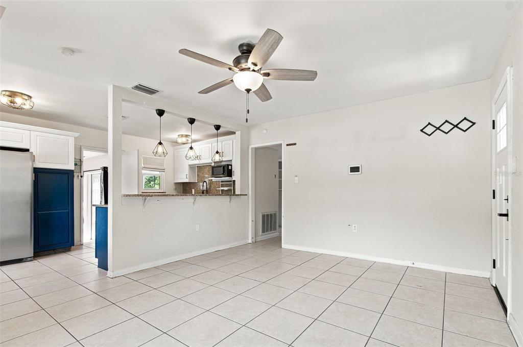 An open-concept kitchen with a breakfast bar and tile flooring overlooks a living area — 2002 E HAMILTON AVENUE, TAMPA, FL