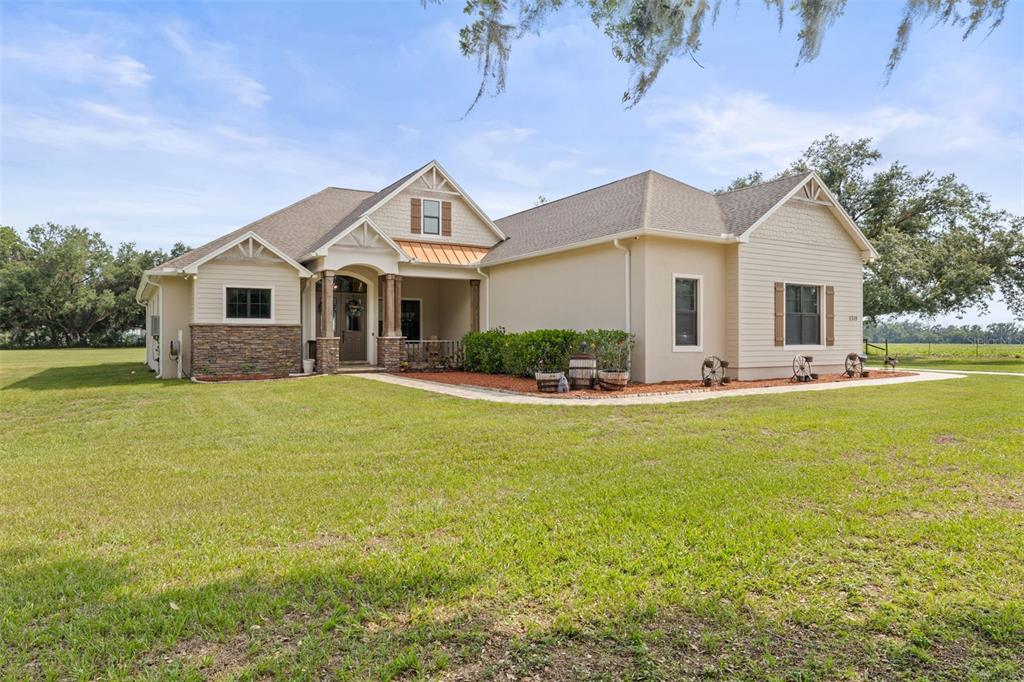 A single-story house with tan siding, stone accents, and a covered entryway sits on grass — 5319 W TRAPNELL ROAD, DOVER, FL