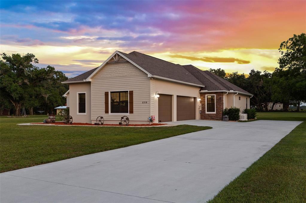 A single-story house with tan siding, a two-car garage, and a concrete driveway at sunset — 5319 W TRAPNELL ROAD, DOVER, FL