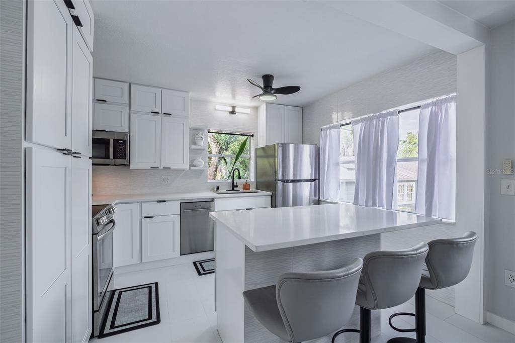 A modern kitchen features white cabinets, stainless steel appliances, and a window above the sink — 1427 ASHER LANE, ORLANDO, FL