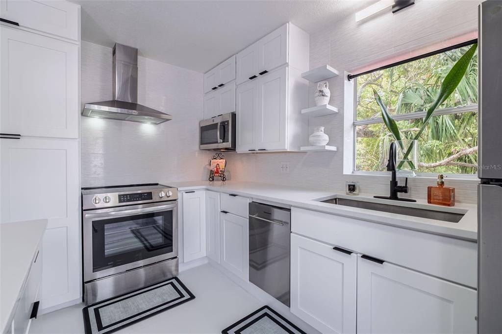 A modern kitchen features white cabinetry, stainless steel appliances, quartz countertops, and an island — 1427 ASHER LANE, ORLANDO, FL