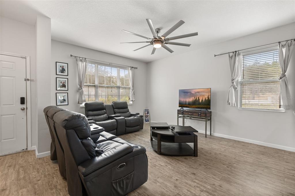 A living room features wood-look flooring, a ceiling fan, leather seating, and two windows — 2427 LINER AVENUE, APOPKA, FL